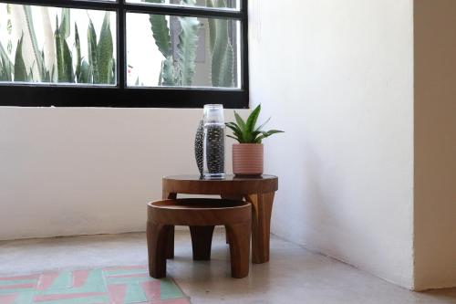 a table with a vase and a stool with a plant on it at Residencia Tropical Don Bonito in Sayulita