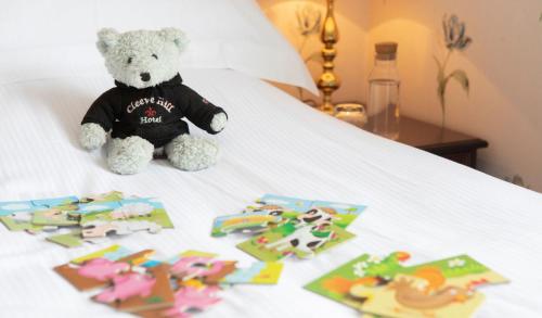 a teddy bear sitting on top of a bed with toys at Cleeve Hill Hotel in Cheltenham