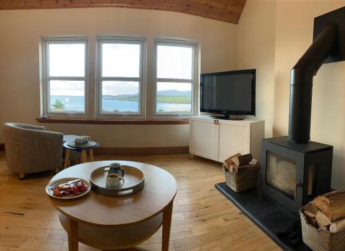 a living room with a wood stove and a tv at Head In The Skye - Healabhal Cottage in Ose
