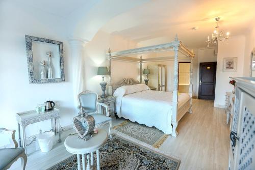a white bedroom with a bed and a chair at Misty Waves Boutique Hotel in Hermanus