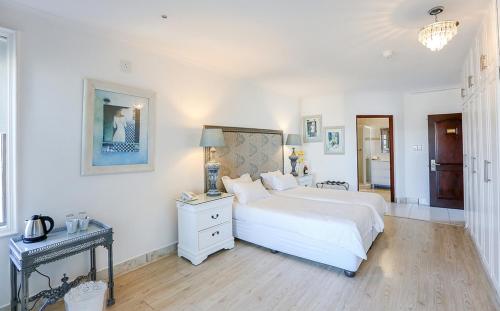 a white bedroom with a large bed and a table at Misty Waves Boutique Hotel in Hermanus