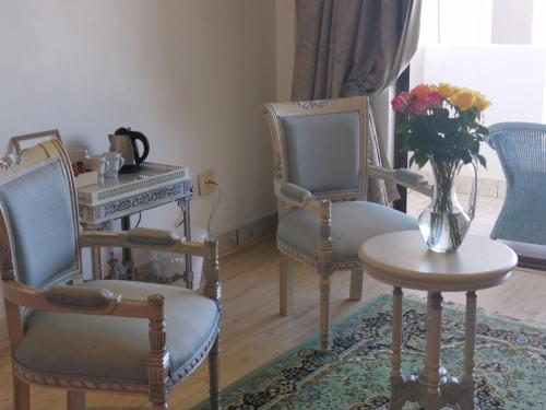 a room with two chairs and a table with a vase of flowers at Misty Waves Boutique Hotel in Hermanus