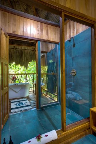 a bathroom with a tub and a glass shower at Sweet Songs Jungle Lodge in San Ignacio