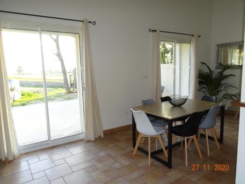 d'une salle à manger avec une table, des chaises et une porte coulissante en verre. dans l'établissement Villa LA BELLE ETOILE, à Étoile-sur-Rhône