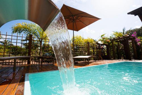 a fountain in a swimming pool with an umbrella at Vila Lua de Taipu - Taipu de Fora in Barra Grande