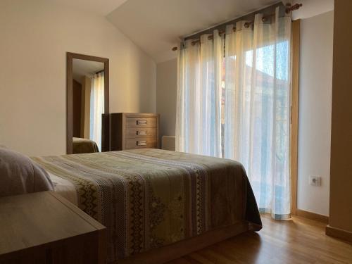 a bedroom with a bed with a dresser and a window at Ático Playa A Xunqueira - Moaña in Moaña