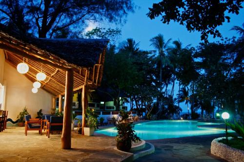 a resort with a swimming pool at night at Plaza Beach Hotel in Bamburi