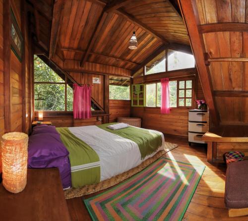 een slaapkamer met een bed in een houten huis bij Mindo Eco Chalet con Rio y Cascada in Mindo