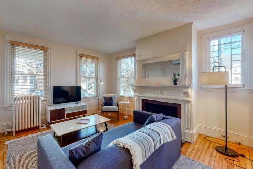 a living room with a blue couch and a fireplace at Albert Meadow Hideaway in Bar Harbor