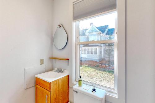 uma casa de banho com um lavatório, um espelho e uma janela em Albert Meadow Hideaway em Bar Harbor