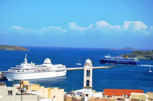 a cruise ship in the water next to a lighthouse at Pefkakia Park in Ermoupoli