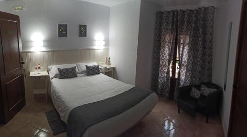 a small bedroom with a bed and a chair at L'Hostalet in Arboli