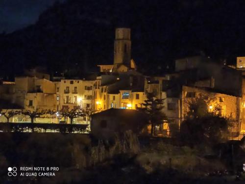 Una ciudad de noche con una iglesia en el fondo en L'Hostalet, en Arboli