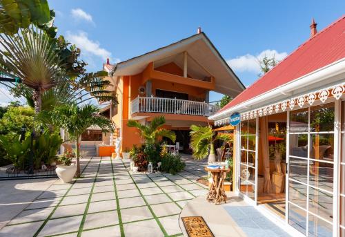 a house with a red roof and a courtyard with palm trees at Oceane Self Catering in La Digue