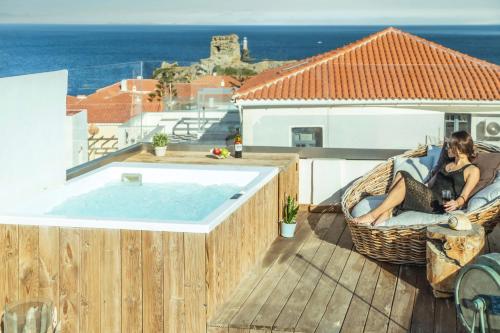 a woman sitting in a chair next to a swimming pool at Castel Abaso Boutique Apartments by Explore Andros in Andros