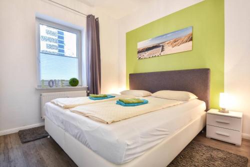 - une chambre avec un grand lit blanc aux murs verts dans l'établissement Villen am Buchenpark 17, à Heringsdorf