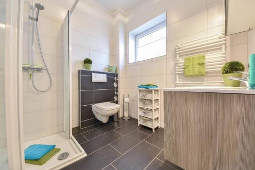 een badkamer met een douche, een toilet en een wastafel bij Villen am Buchenpark 17 in Heringsdorf