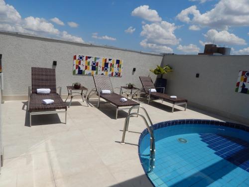 a patio with chairs and a swimming pool on a roof at Mercure Sao Paulo Moema in Sao Paulo