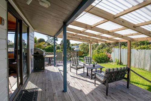 a patio with a table and chairs and a grill at Driftwood Cottage in Punakaiki