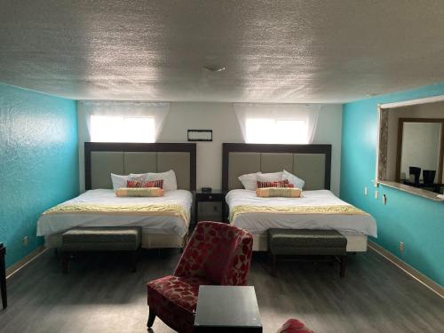 a room with two beds and a chair and a mirror at Nampa Inn & Suites in Nampa