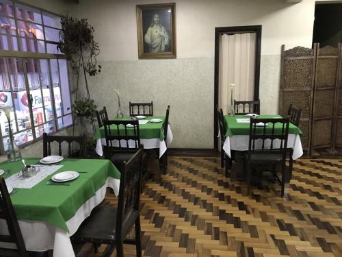 a dining room with two green tables and chairs at Hotel Maristela in São Joaquim