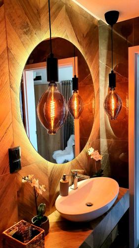 a bathroom with a sink and a mirror with lights at Villa Olimpijska 2 - Centrum in Wisła