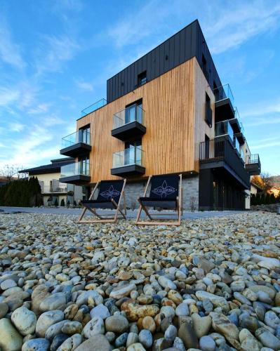 a building with two chairs sitting on a rocky beach at Villa Olimpijska 2 - Centrum in Wisła