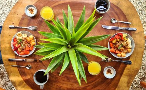 Mikasa Bacalar Hotel Boutique, Lagoon Front في باكالار: طاولة خشبية عليها أطباق طعام ونبتة