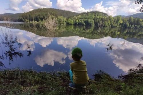 a young boy sitting in front of a lake at Apartmán Staré Hamry in Staré Hamry