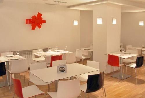 a restaurant with white tables and chairs and a red star on the wall at Hotel Trefacio in Zamora