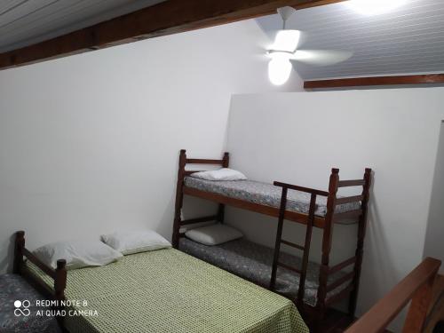 a room with two bunk beds and a ceiling fan at Maranduba Ville II in Ubatuba