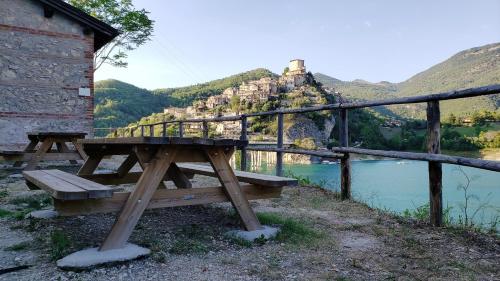 a wooden picnic table next to a fence and a body of water at Amazing Lake View in Castel di Tora