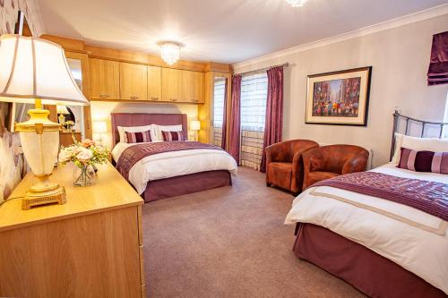 a hotel room with two beds and a desk with a lamp at Westlea Guest House in Alnmouth