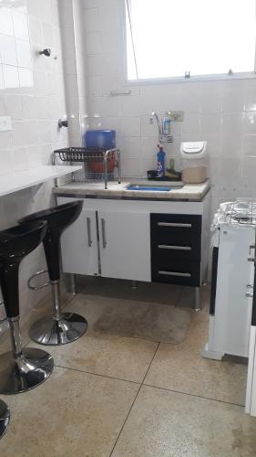 a kitchen with a sink and a counter with a stool at Apartamento mobiliado prédio frente ao mar in São Vicente