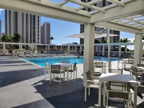 a patio with tables and chairs next to a pool at LSI Resorts at Ala Moana in Honolulu