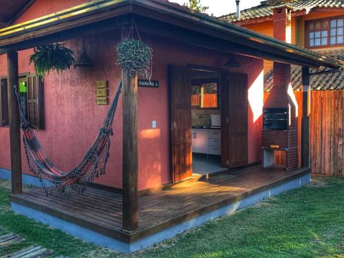 a porch of a house with a hammock on it at Luz da Lua Cabanas Comfort in Praia do Rosa