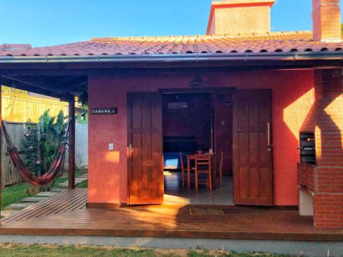 a small house with a wooden deck with a table at Luz da Lua Cabanas Comfort in Praia do Rosa