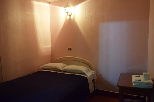 a small room with a bed with a light on the wall at Hotel Posada del Centro in Guatemala