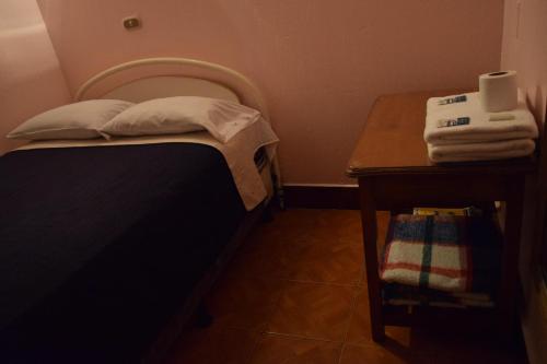a small bedroom with a bed and a wooden table at Hotel Posada del Centro in Guatemala