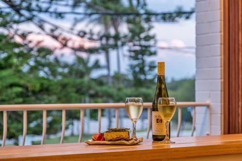 a bottle of wine and two glasses on a balcony at The Terrace Penthouse Apartment in Brunswick Heads