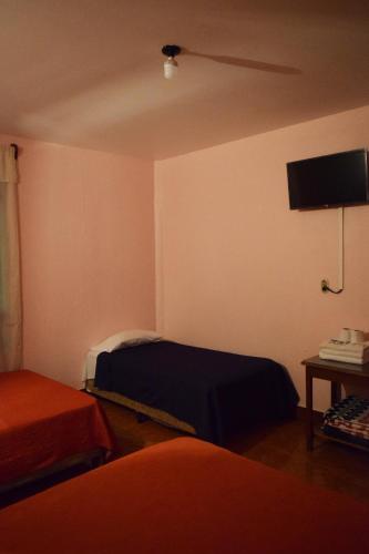a room with two beds and a flat screen tv at Hotel Posada del Centro in Guatemala