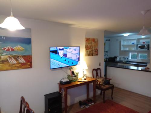 a living room with a table and a television on a wall at Lomas Papudo 4 in Papudo