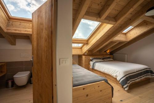 two beds in a room with wooden ceilings at Casa Ekharle - Affittacamere in Rotzo