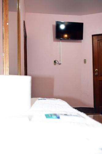 a room with a bed and a tv on the wall at Hotel Posada del Centro in Guatemala