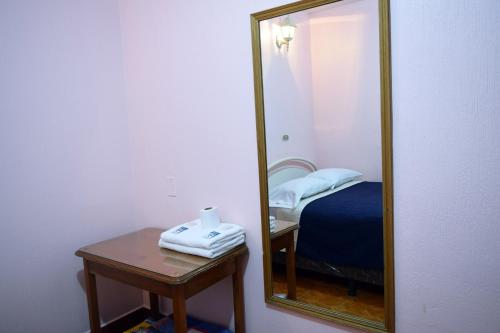a mirror in a room with a bed and a table at Hotel Posada del Centro in Guatemala