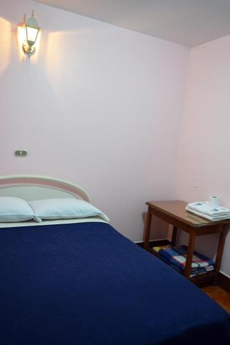 a bedroom with a blue bed and a table at Hotel Posada del Centro in Guatemala