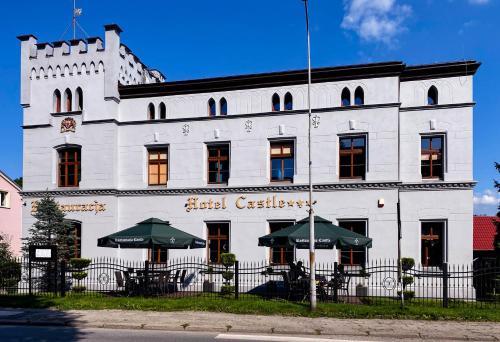 a white building with umbrellas in front of it at Hotel i Restauracja Castle in Bystrzyca Kłodzka