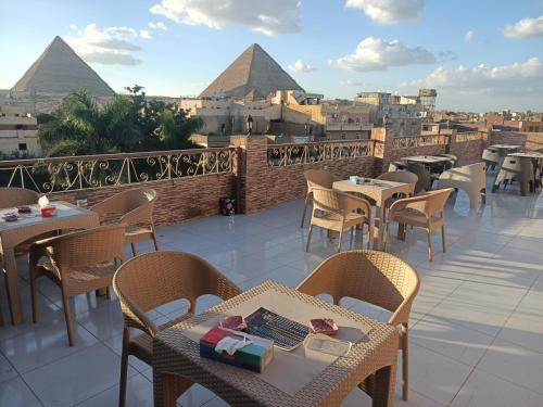 un patio con tavoli e sedie con piramidi sullo sfondo di Makadi Pyramids View a Il Cairo