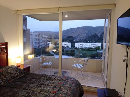 a bedroom with a bed and a balcony with a view at Lomas Papudo 4 in Papudo