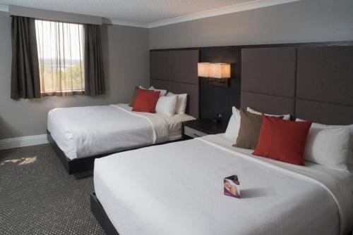 a hotel room with two beds with red pillows at Crowne Plaza Fredericton Lord Beaverbrook by IHG in Fredericton